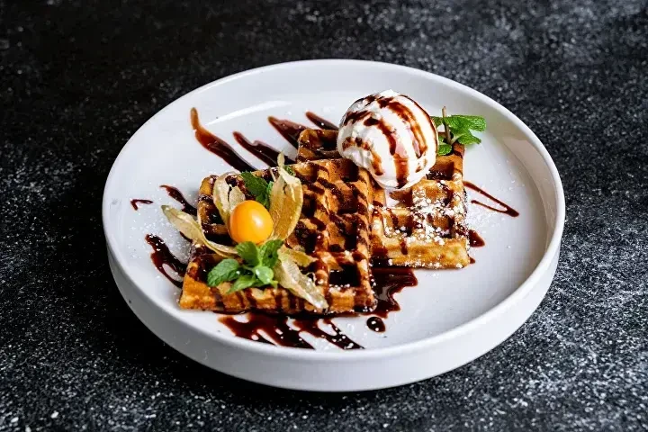 Бельгийская вафля с бананом, орехами и мороженым под шоколадом